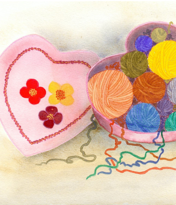 Pelotes de laines de diverses couleurs dans une boîte en forme de cœur.